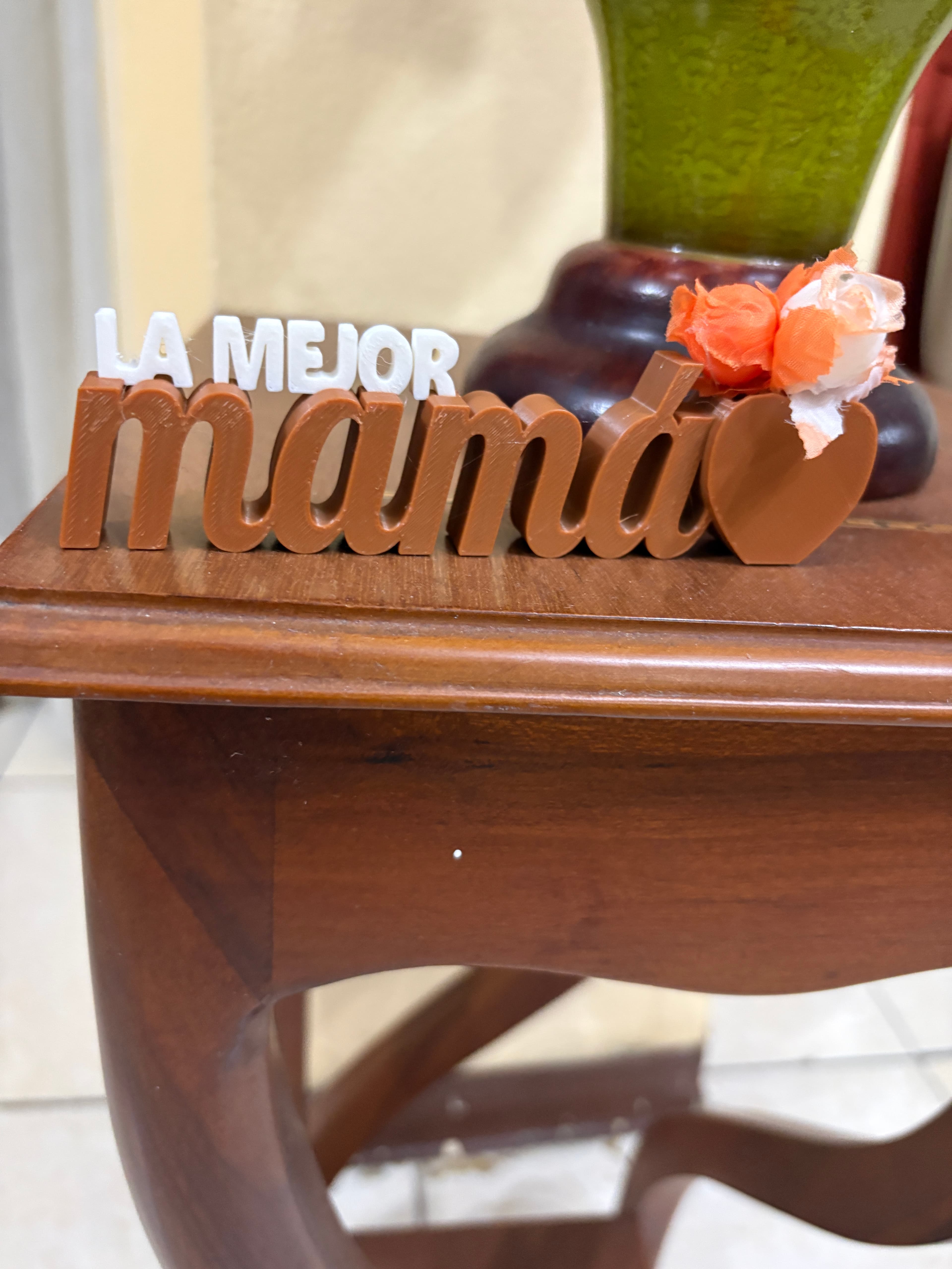 Cartel La mejor mamá apoyado sobre una mesa